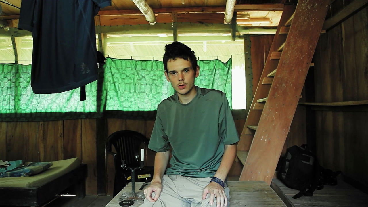 A white young man looking dazed in a wooden cabin