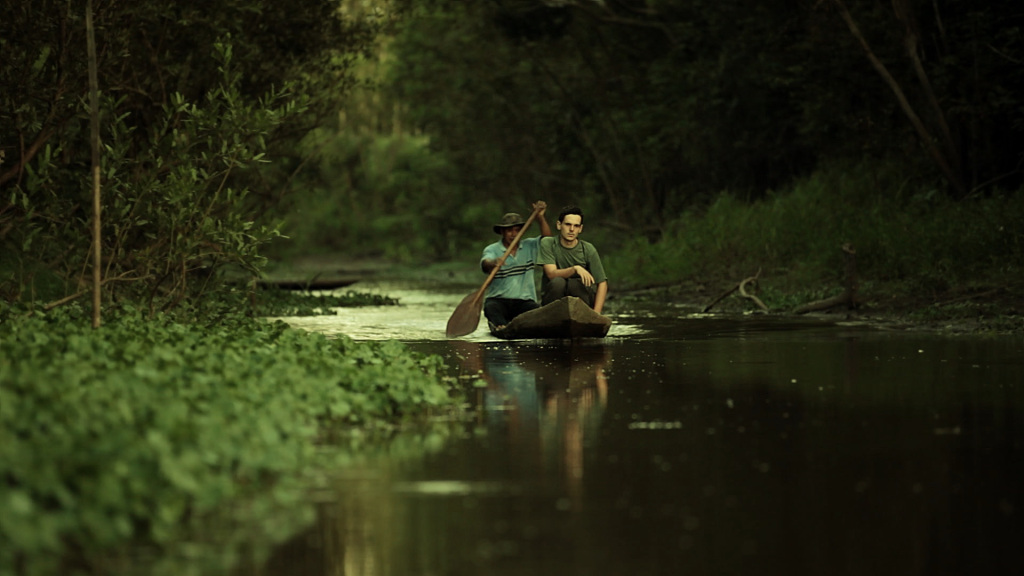 A white young man looking lost in a canoe in a dark river 