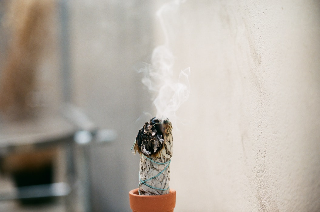 A wage stick burning upwards in a brown pot